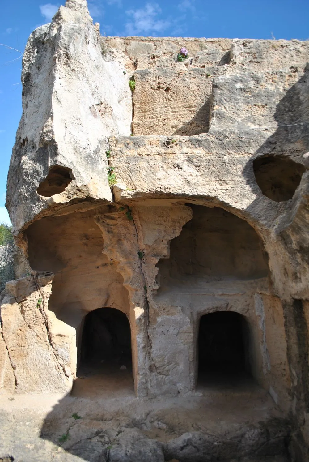 Ancient rock-cut tomb entrances in a stone cliff face in Cyprus
